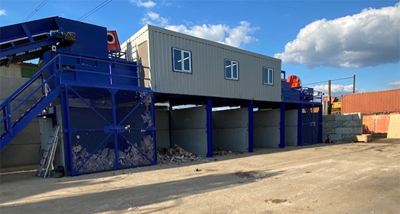 industrial waste processing facility with blue structures and five storage bins