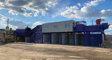 industrial recycling equipment with two operational units and blue structures under a cloudy sky